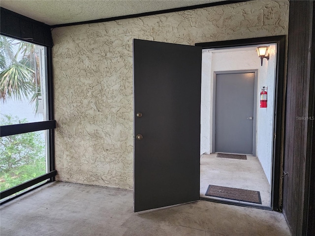 spare room with concrete flooring, a wealth of natural light, and a textured ceiling