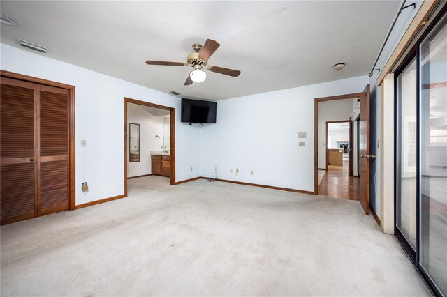 unfurnished bedroom featuring ceiling fan, light colored carpet, and ensuite bathroom