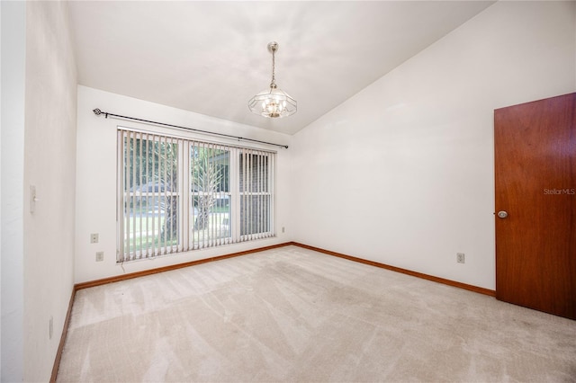 carpeted empty room with lofted ceiling and a chandelier