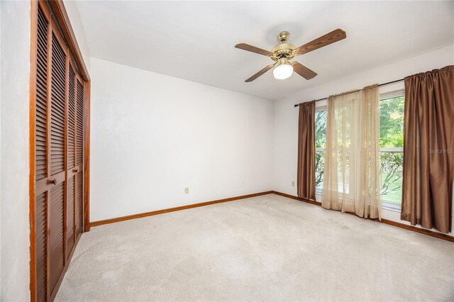 unfurnished bedroom with light colored carpet, ceiling fan, and a closet