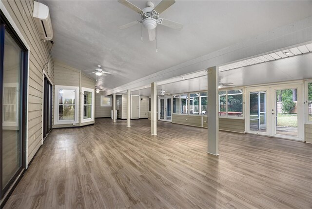 unfurnished sunroom with lofted ceiling, a wall mounted air conditioner, and ceiling fan