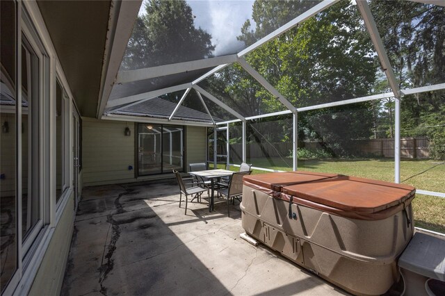 view of patio featuring glass enclosure and a hot tub