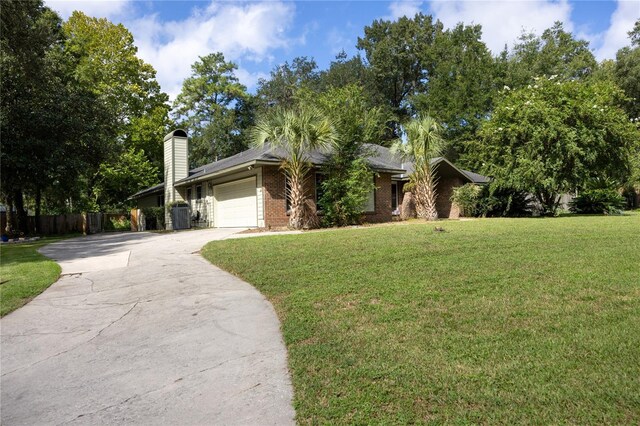 view of front of property with a garage, a front lawn, and central AC