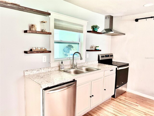 kitchen featuring light wood-type flooring, white cabinetry, island exhaust hood, sink, and appliances with stainless steel finishes