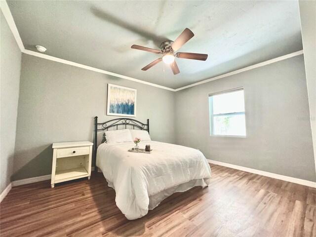 bedroom with crown molding, ceiling fan, and dark hardwood / wood-style floors