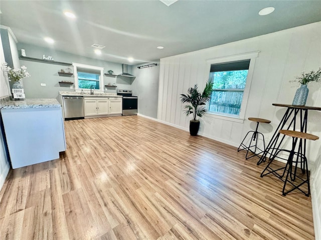 kitchen featuring white cabinets, light wood-type flooring, appliances with stainless steel finishes, light stone countertops, and sink