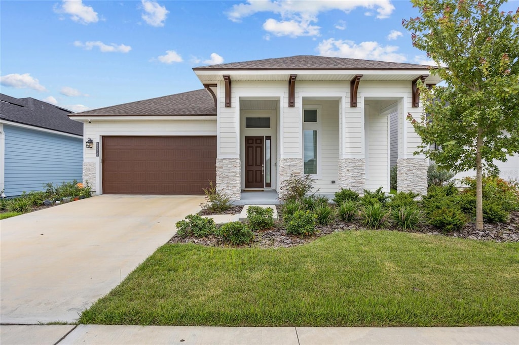 prairie-style home featuring a garage and a front lawn