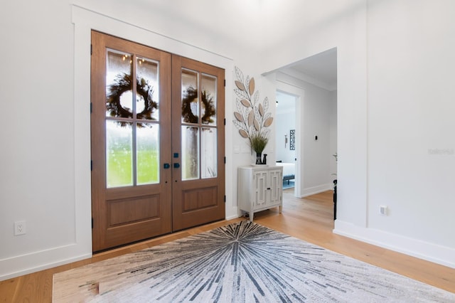 entrance foyer featuring crown molding, light hardwood / wood-style floors, and french doors