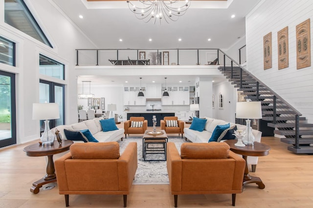 living room with light hardwood / wood-style flooring, a high ceiling, and an inviting chandelier