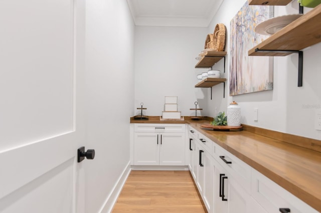 bar featuring light hardwood / wood-style floors, white cabinets, crown molding, and wooden counters