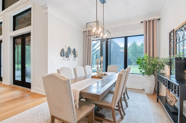 dining space with light hardwood / wood-style flooring, crown molding, french doors, and an inviting chandelier