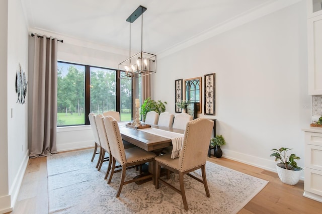 dining space with an inviting chandelier, ornamental molding, and light wood-type flooring