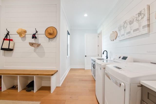 laundry room with washer and clothes dryer, cabinets, sink, light hardwood / wood-style flooring, and crown molding