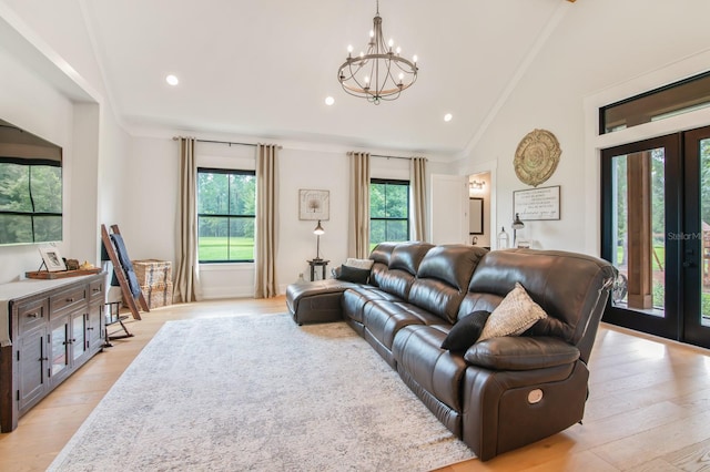 living room with light hardwood / wood-style flooring, a notable chandelier, lofted ceiling, and french doors