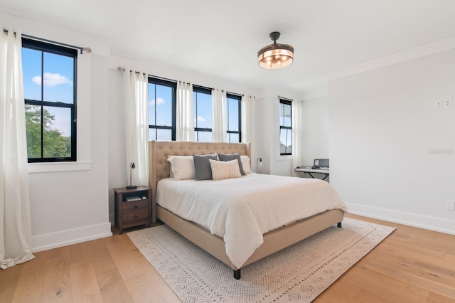 bedroom with crown molding and light hardwood / wood-style flooring