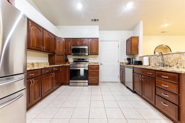 kitchen with light tile patterned flooring, sink, light stone countertops, and stainless steel appliances