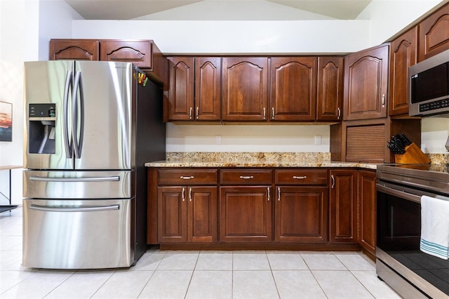 kitchen with light stone counters, light tile patterned floors, and appliances with stainless steel finishes