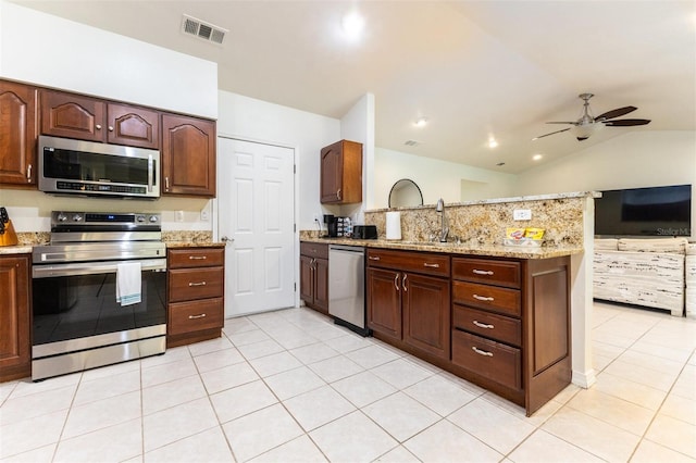 kitchen with light stone countertops, stainless steel appliances, vaulted ceiling, ceiling fan, and light tile patterned floors