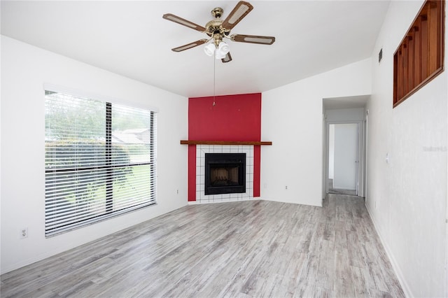 unfurnished living room with vaulted ceiling, ceiling fan, a tile fireplace, and hardwood / wood-style flooring