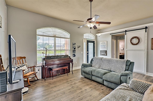 living room featuring a barn door, ceiling fan, and hardwood / wood-style flooring