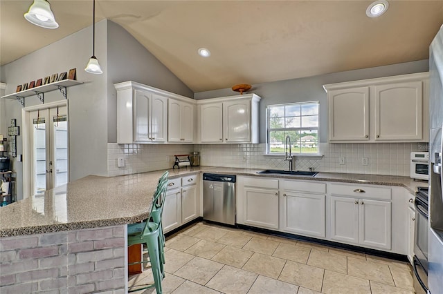 kitchen featuring a sink, a peninsula, white cabinets, and stainless steel dishwasher