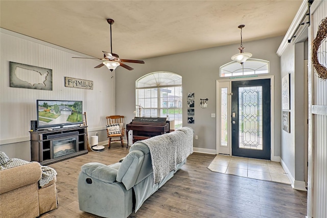 living area featuring a ceiling fan, a fireplace, baseboards, and wood finished floors