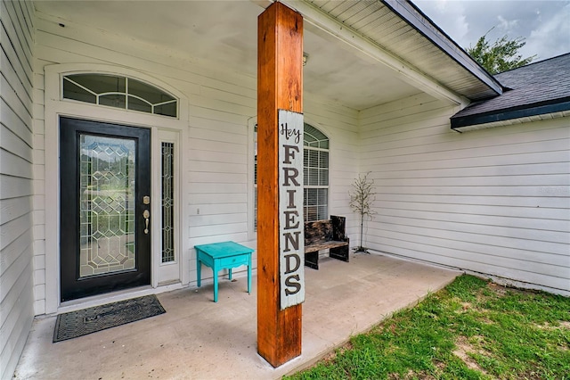 doorway to property featuring a porch and roof with shingles