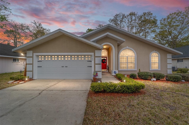 view of front facade featuring stucco siding, concrete driveway, and an attached garage