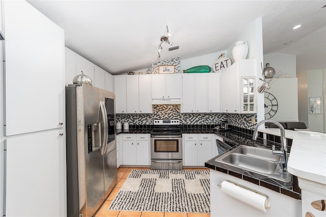 kitchen featuring white cabinets, appliances with stainless steel finishes, sink, lofted ceiling, and light tile patterned flooring