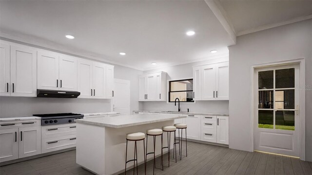 kitchen with stainless steel gas cooktop, a kitchen island, a breakfast bar area, and white cabinets