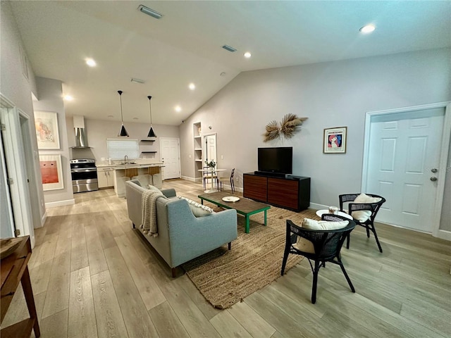 living room featuring sink, light hardwood / wood-style flooring, and high vaulted ceiling