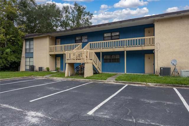 view of property featuring stairs, uncovered parking, and central AC