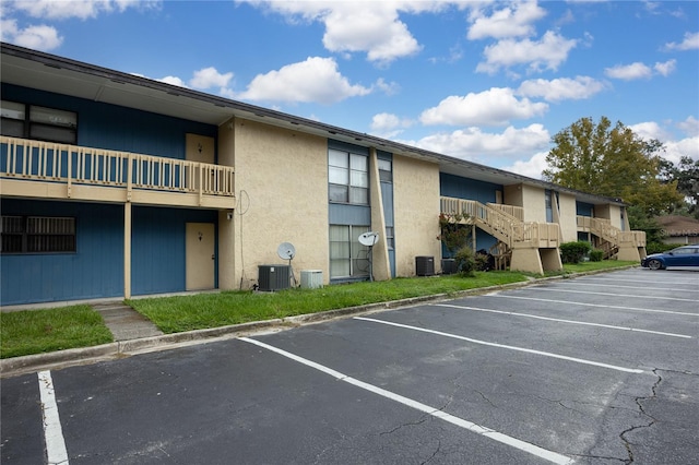 view of building exterior with cooling unit and uncovered parking