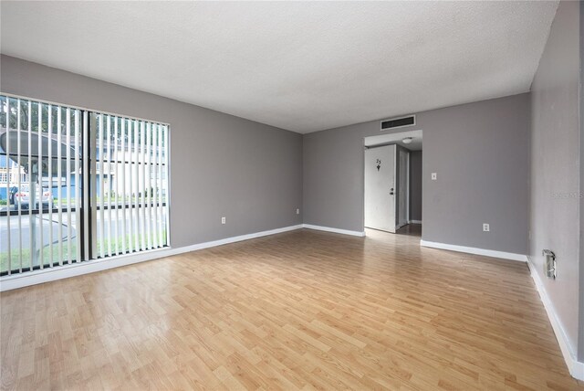 unfurnished room with a textured ceiling and light hardwood / wood-style floors