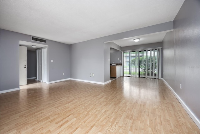 spare room with a textured ceiling and light hardwood / wood-style flooring