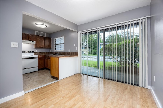 kitchen with visible vents, under cabinet range hood, a sink, white range with electric stovetop, and light wood-style floors