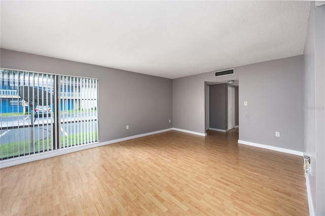 spare room with a textured ceiling and light wood-type flooring