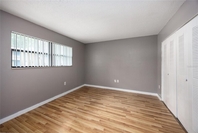 unfurnished bedroom featuring multiple windows, light hardwood / wood-style flooring, and a closet