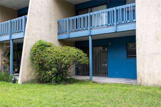 entrance to property featuring stucco siding and a yard