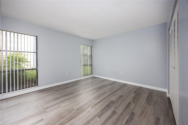 unfurnished bedroom featuring multiple windows, wood-type flooring, and a textured ceiling