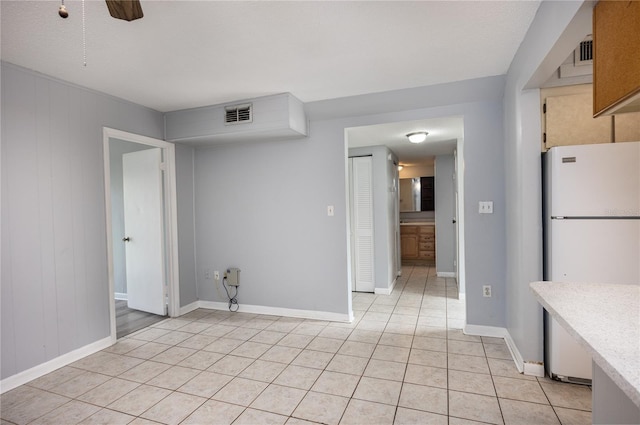 interior space with light tile patterned floors, ceiling fan, white refrigerator, and a textured ceiling