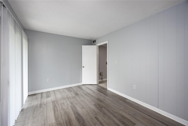 unfurnished bedroom with visible vents, baseboards, a textured ceiling, and wood finished floors