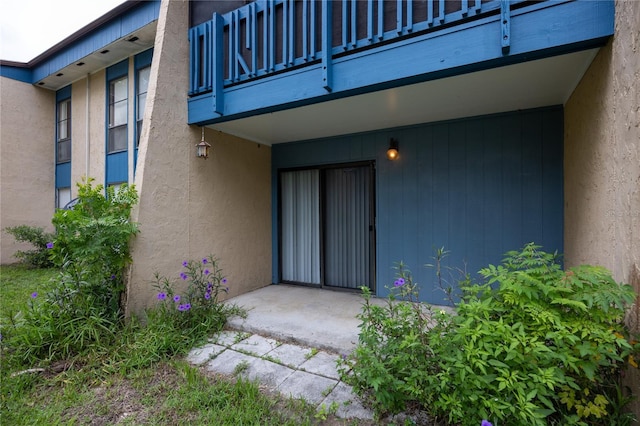 doorway to property featuring stucco siding and a balcony