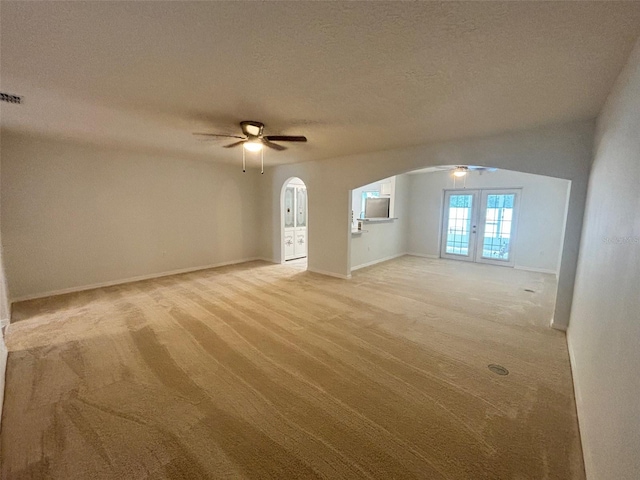 empty room featuring a textured ceiling, ceiling fan, carpet floors, and french doors