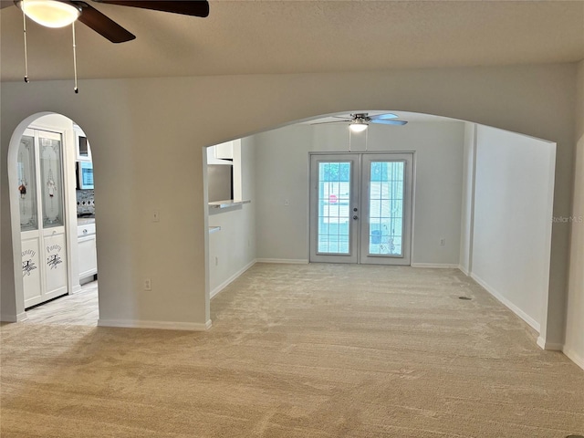 carpeted empty room with a textured ceiling, ceiling fan, and french doors