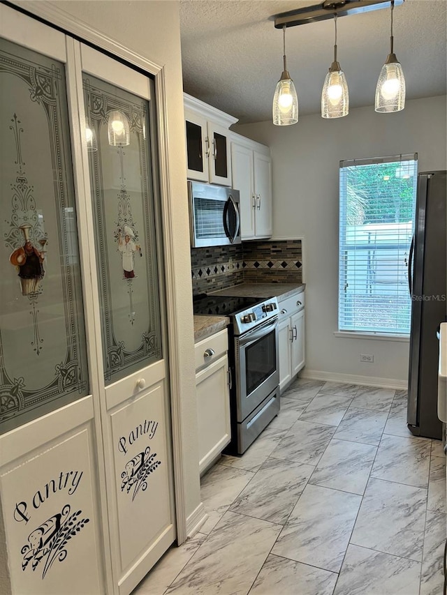 kitchen with pendant lighting, tasteful backsplash, stainless steel appliances, and white cabinets