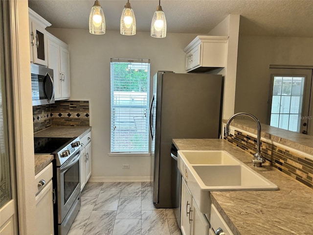 kitchen with a healthy amount of sunlight, stainless steel appliances, backsplash, and white cabinetry