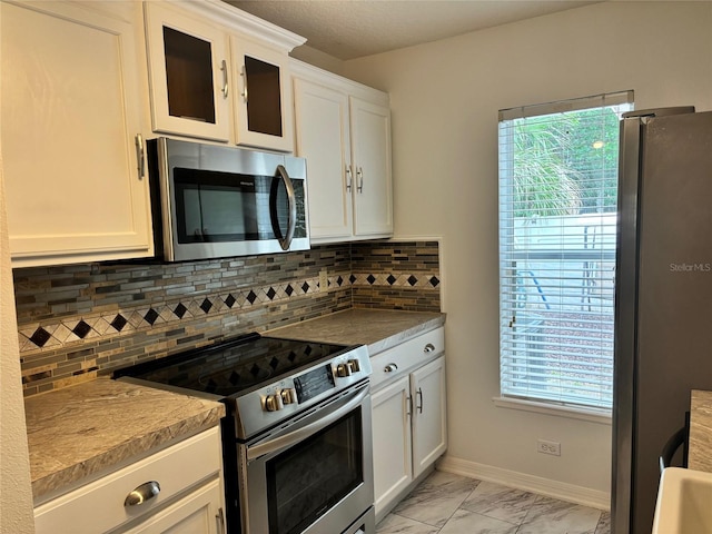 kitchen with appliances with stainless steel finishes, white cabinetry, and decorative backsplash