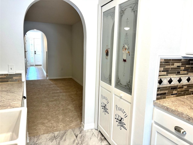 interior space with light colored carpet, decorative backsplash, and white cabinetry