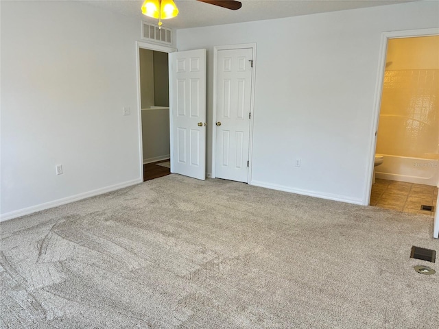 unfurnished bedroom featuring connected bathroom, carpet floors, and ceiling fan